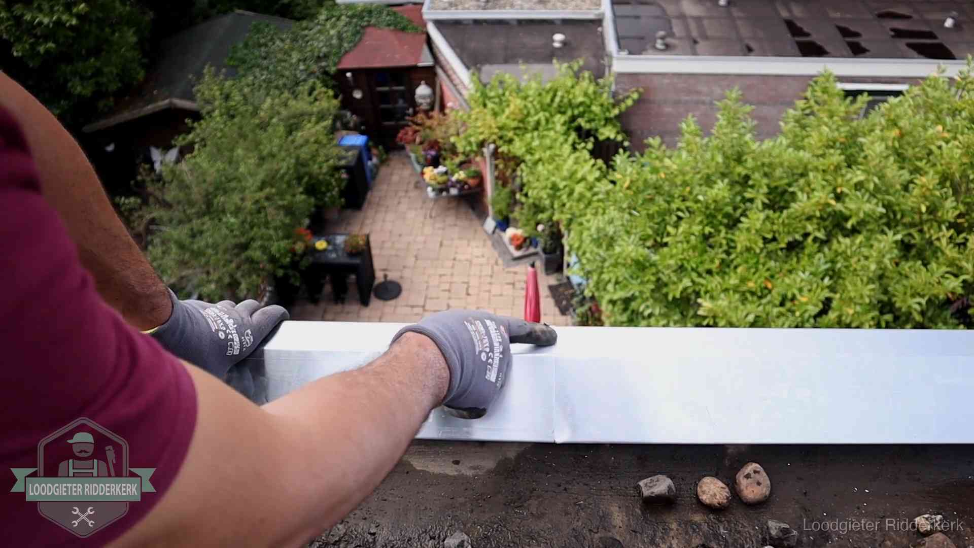 Vakman plaatst een daktrim op de dakrand van een woning in Ridderkerk