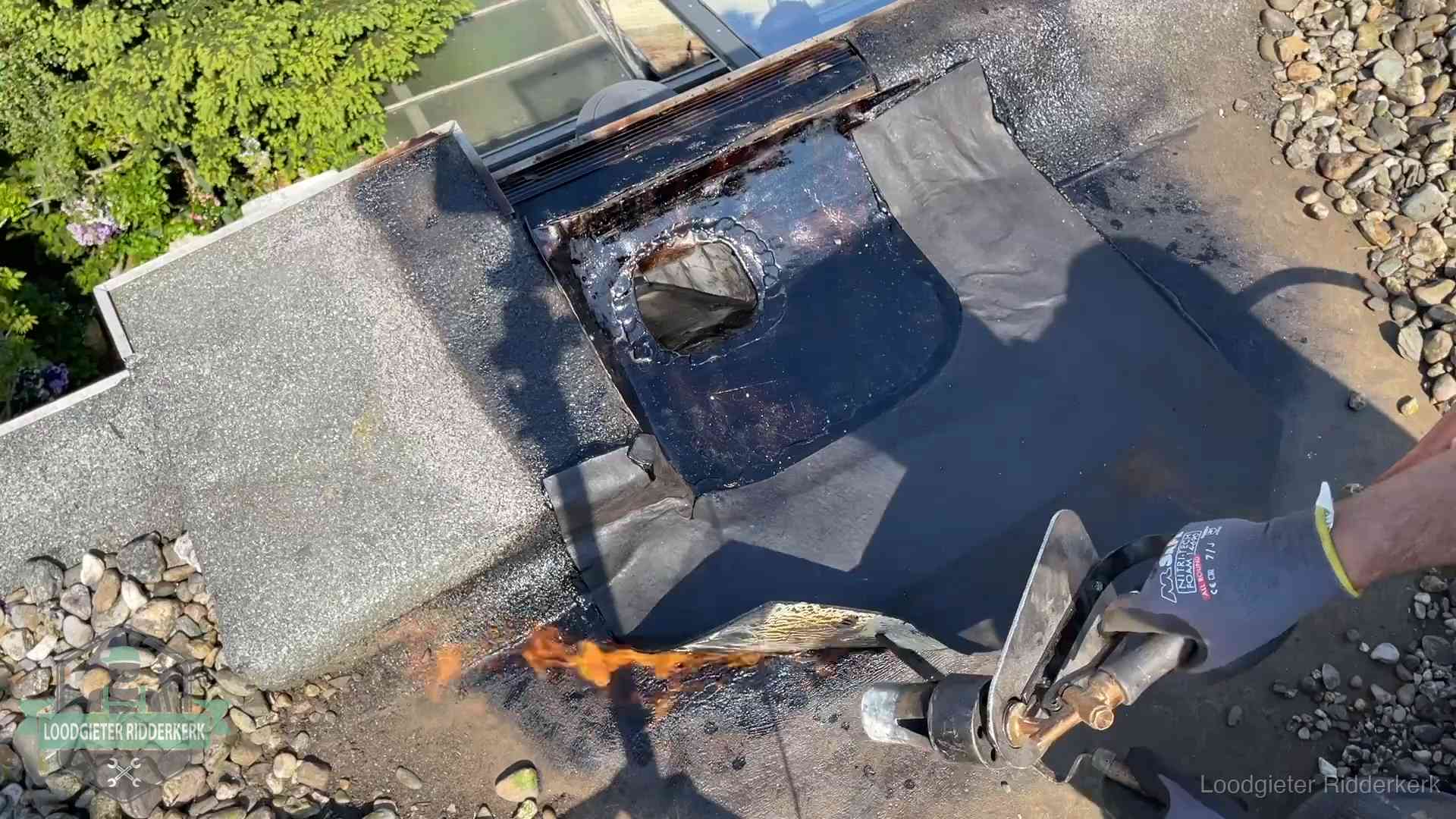 Dakdekker brandt bitumen rond een doorvoer tijdens een daklekkage-reparatie in Ridderkerk