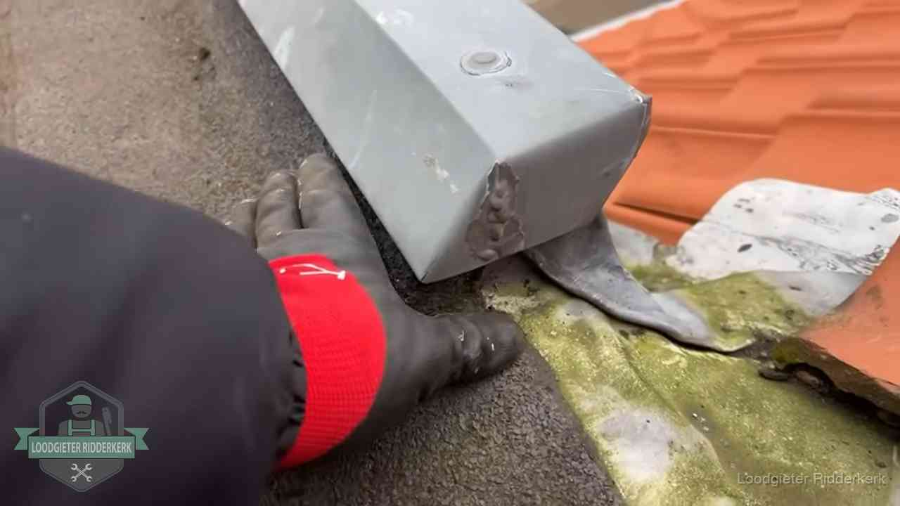 Controle van een zinken hemelwaterafvoer met loodslab bij dakpannen in Ridderkerk