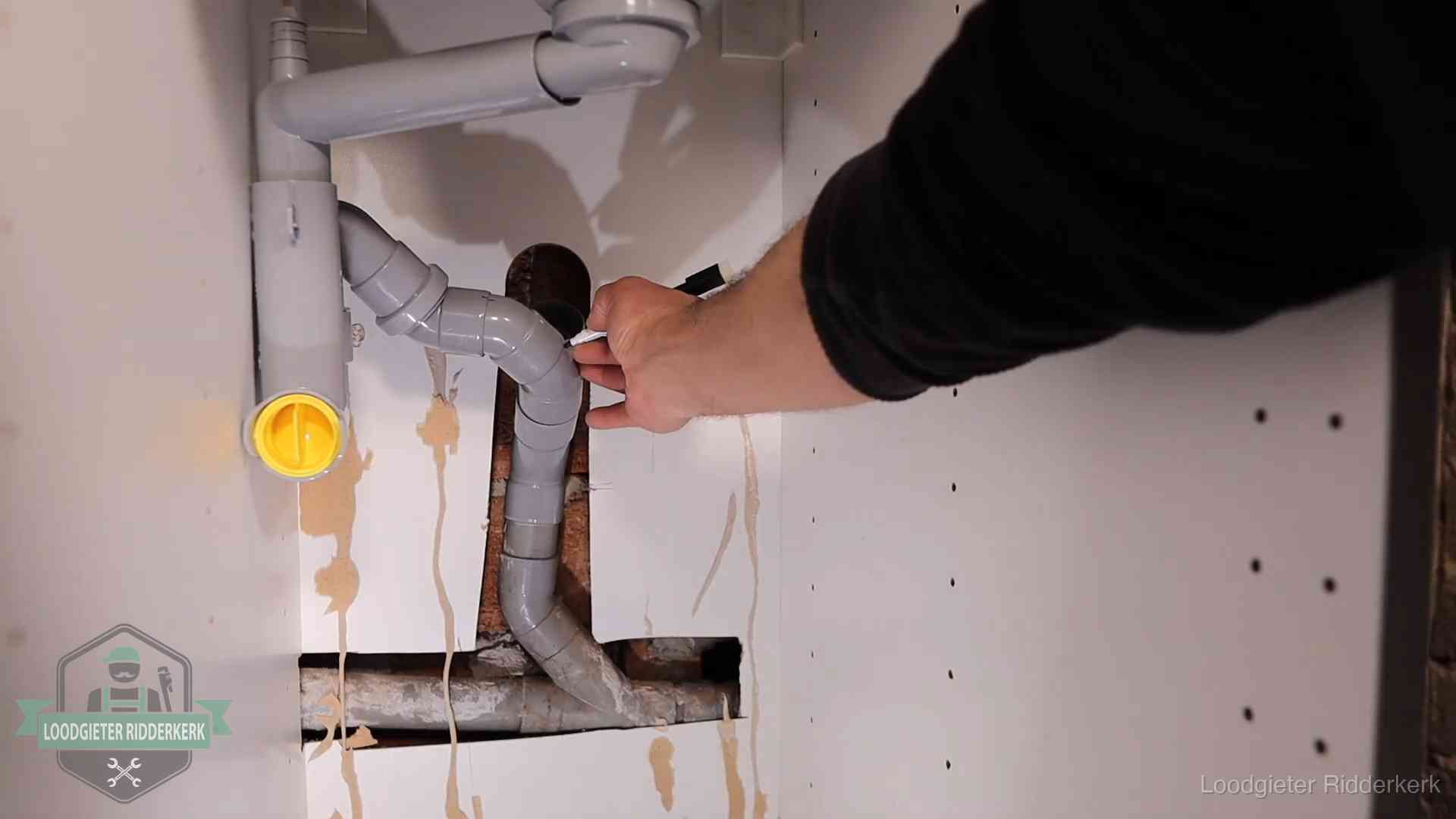 Loodgieter voor verhuurders en bedrijven in Ridderkerk Loodgieter markeert een pvc-afvoerbuis onder een gootsteen in Ridderkerk