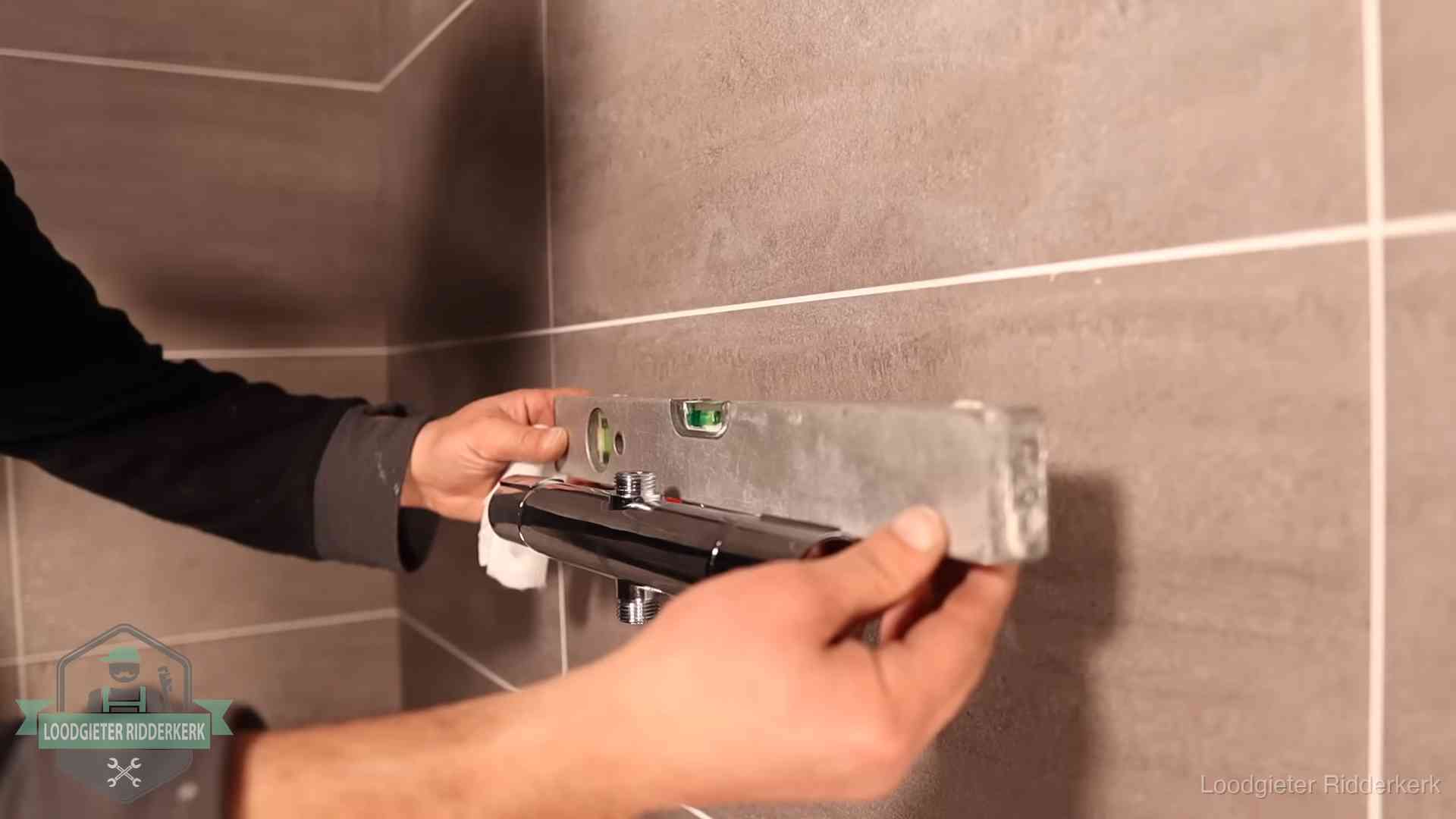 Loodgietersbedrijf voor sanitair in Ridderkerk Loodgieter lijnt een douchekraan uit met een waterpas in een woning in Ridderkerk
